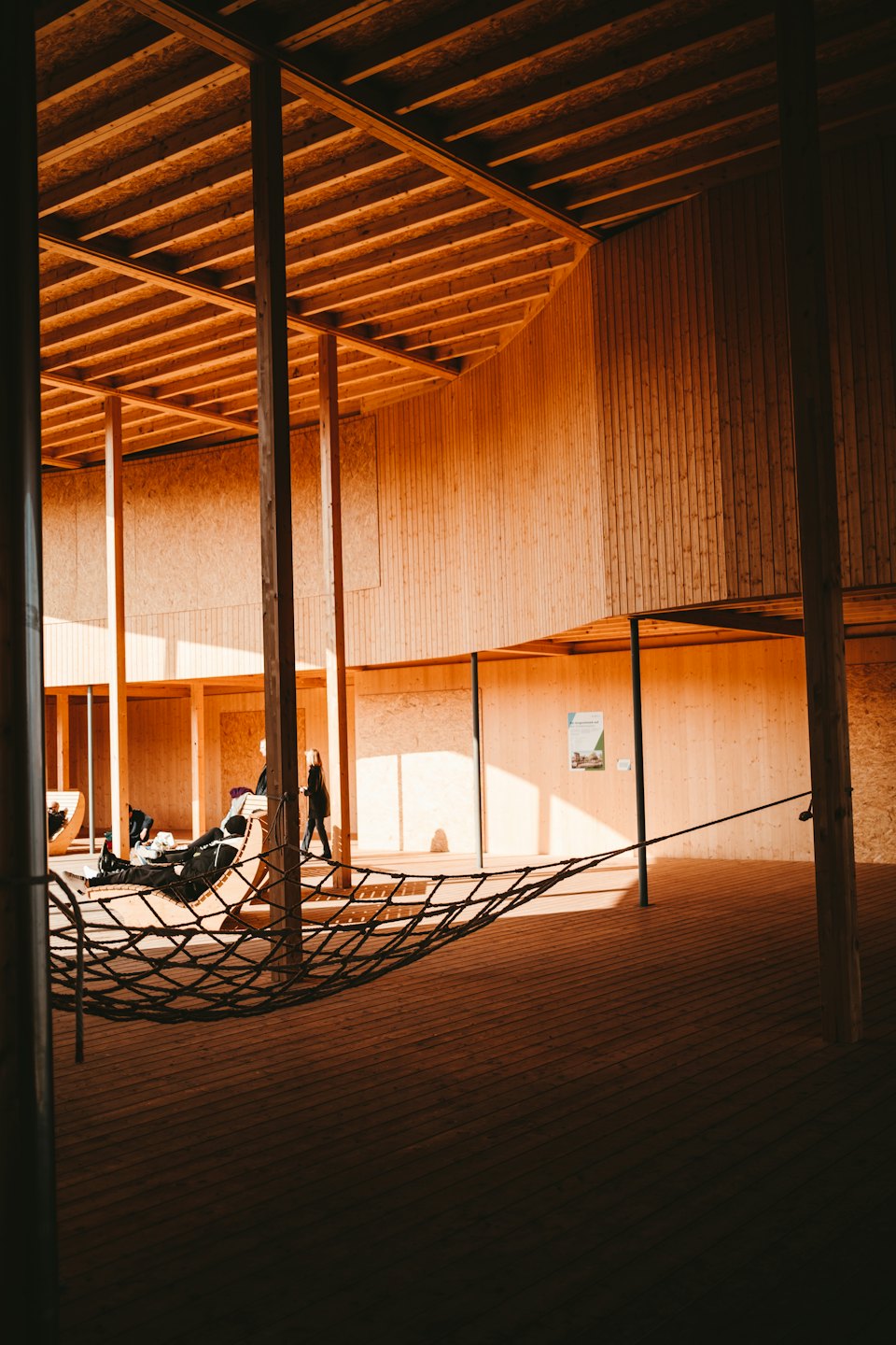 People relax in a modern wooden building with exposed beams.