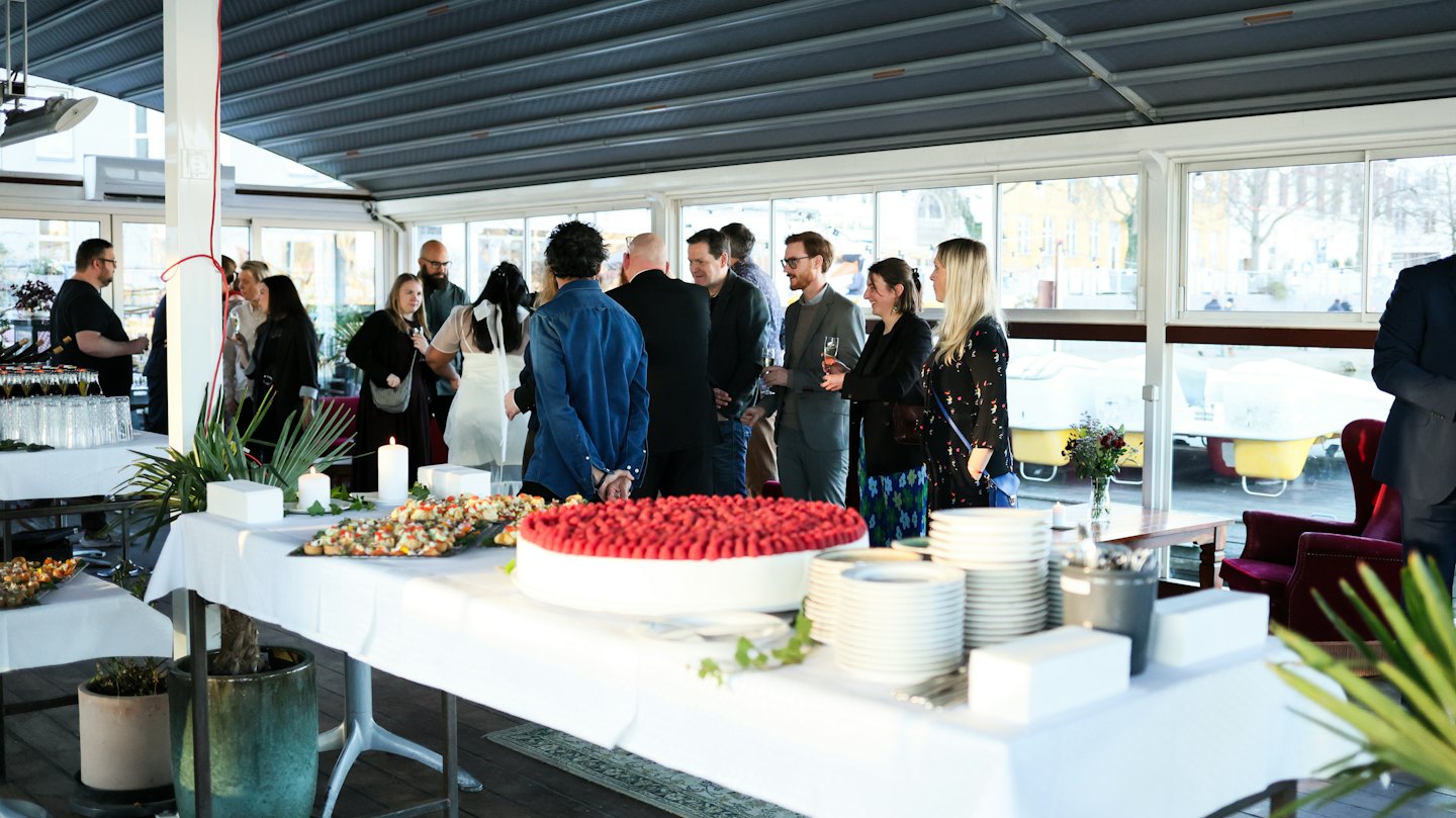 Diverse people gather around a buffet table at an indoor event.