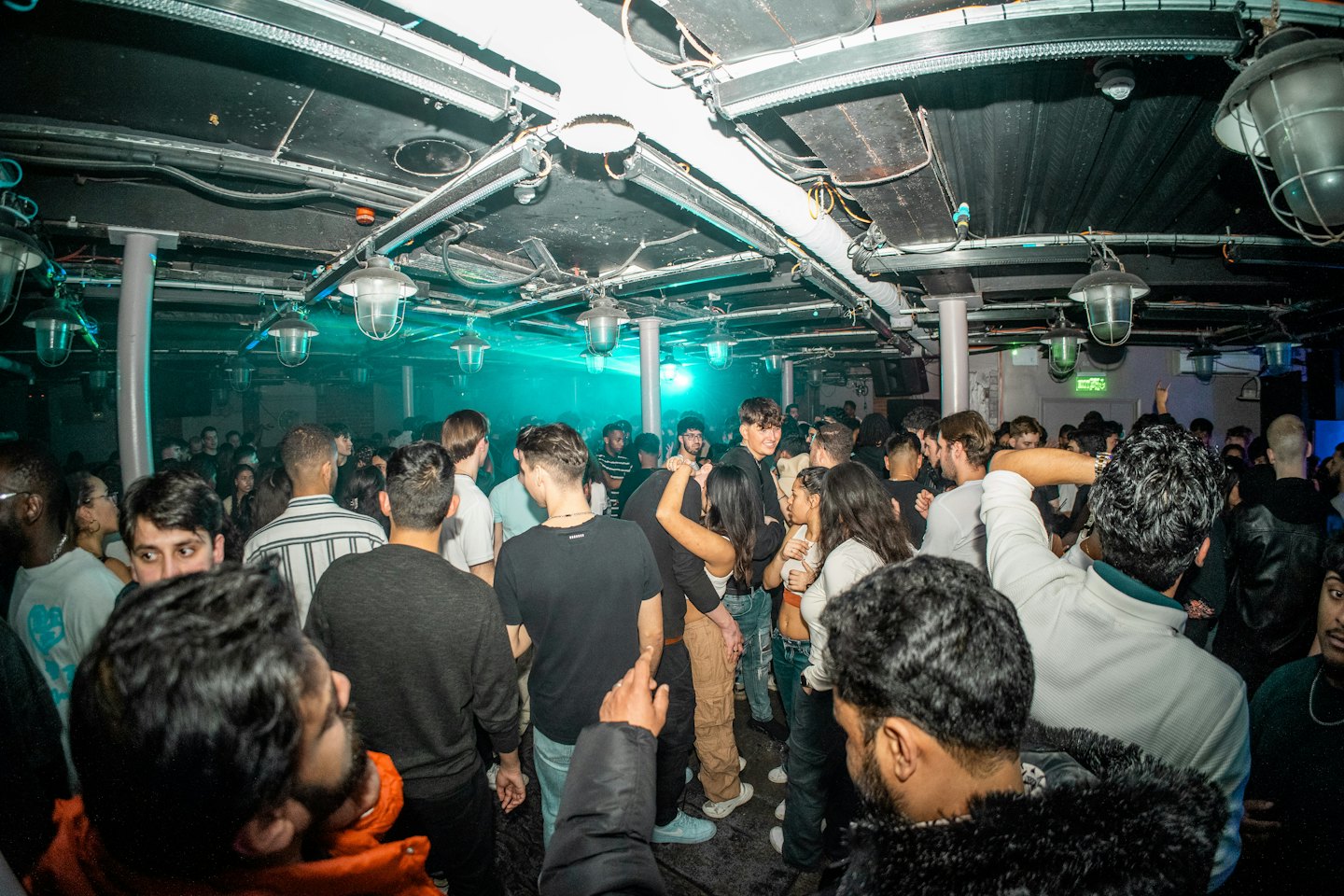 A group of people dances together inside a crowded club.