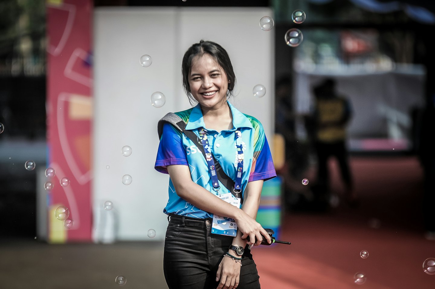 Young woman smiles holding a walkie-talkie with bubbles.